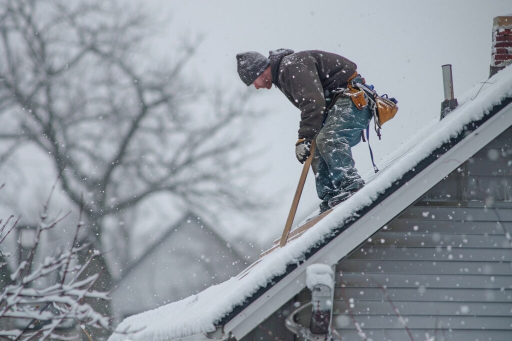 A photo of a roofer from Manitoba Roofers doing maintenance work on a Winnipeg roof during winter, snow covered Winnipeg residential house
